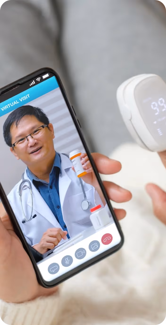 Male doctor wearing glasses and a white coat with a stethoscope around his neck, sitting at a desk with hands clasped.