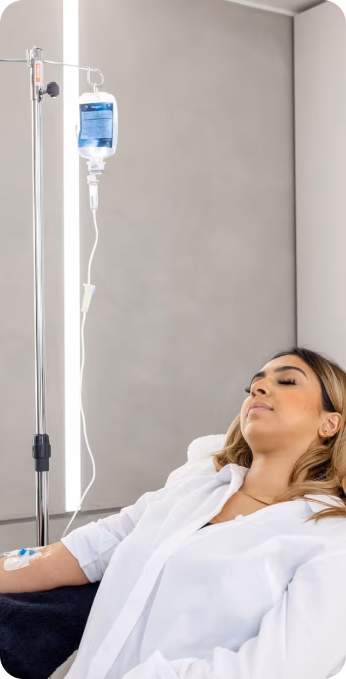 Male doctor wearing glasses and a white coat with a stethoscope around his neck, sitting at a desk with hands clasped.