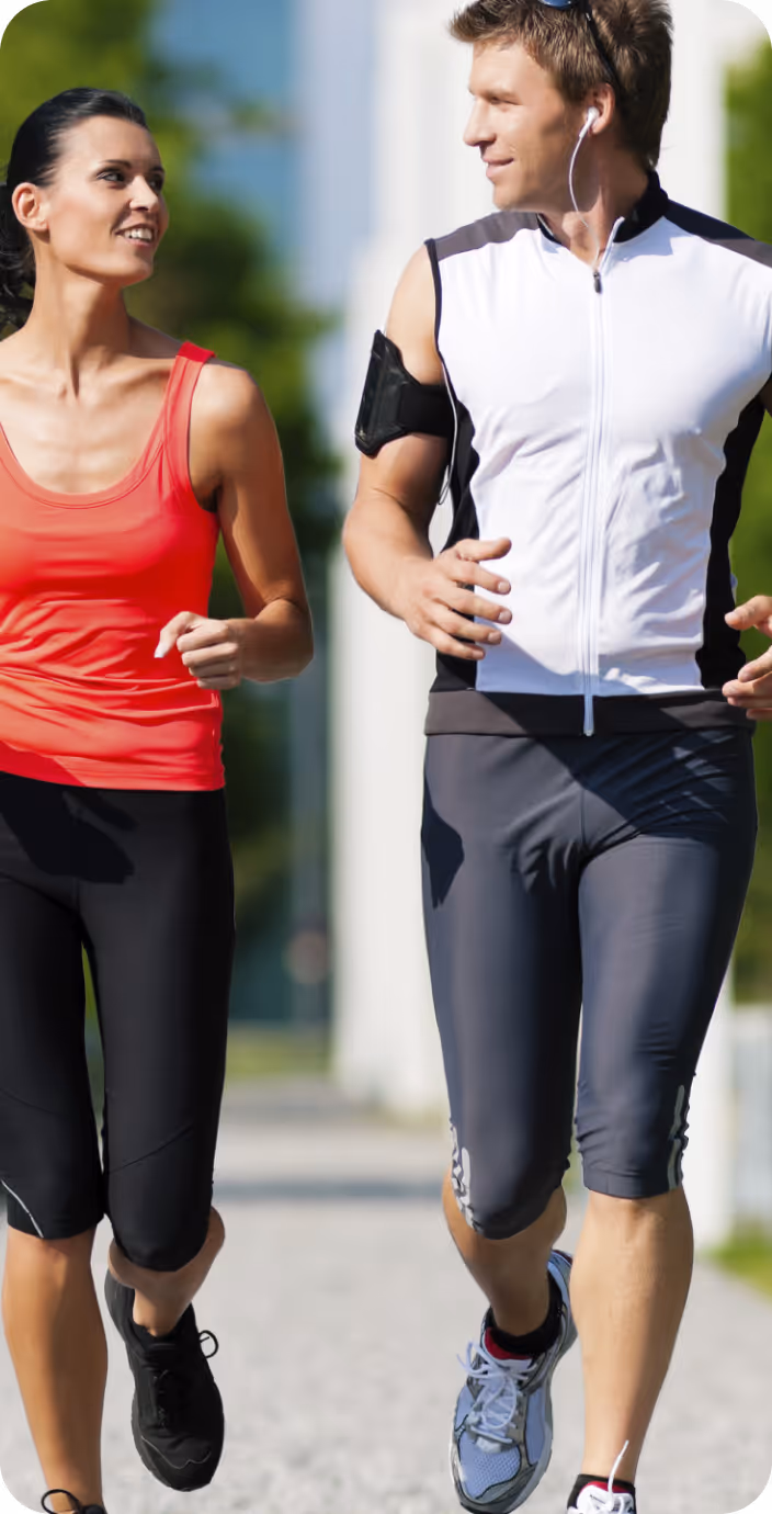 Male doctor wearing glasses and a white coat with a stethoscope around his neck, sitting at a desk with hands clasped.