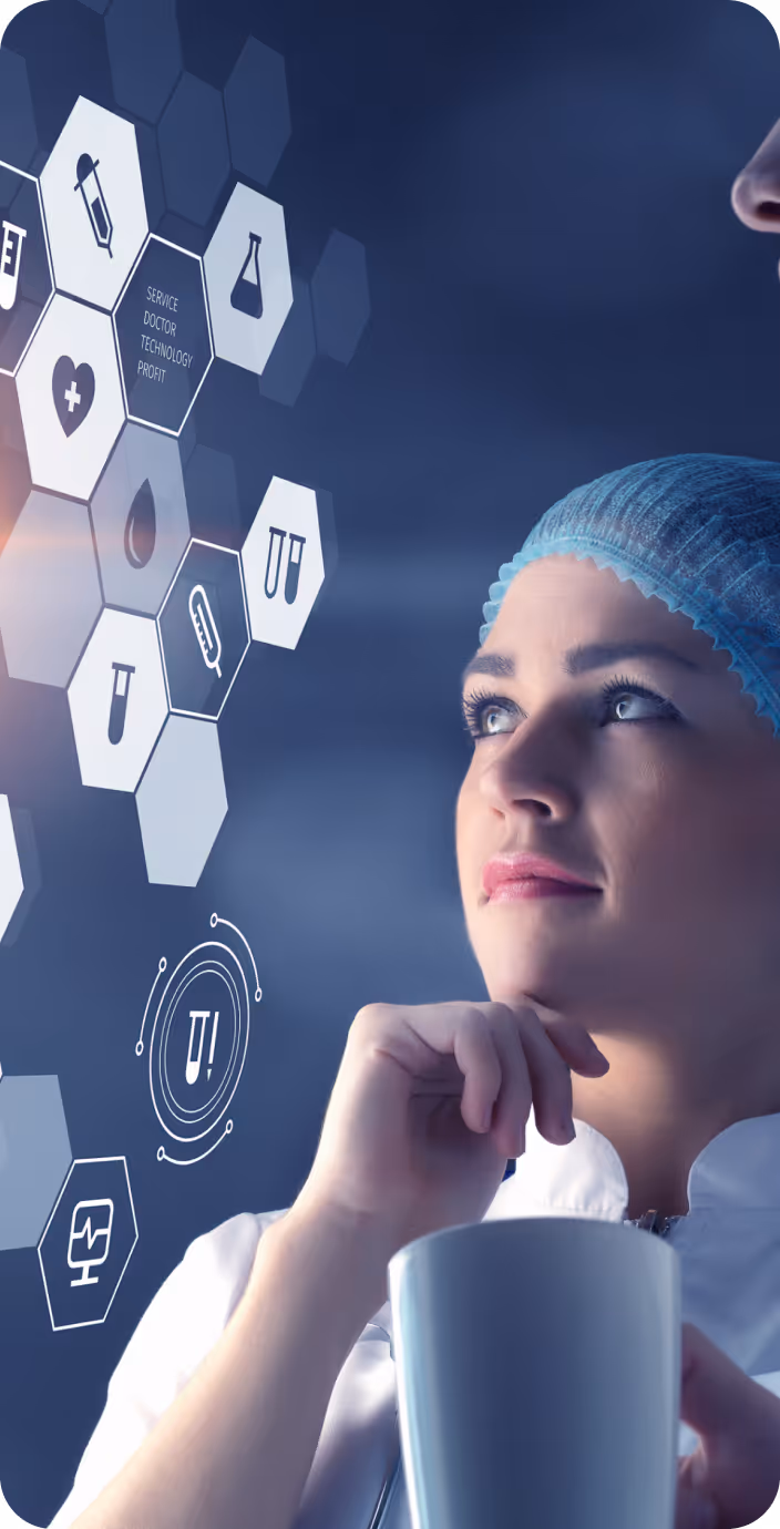 Male doctor wearing glasses and a white coat with a stethoscope around his neck, sitting at a desk with hands clasped.