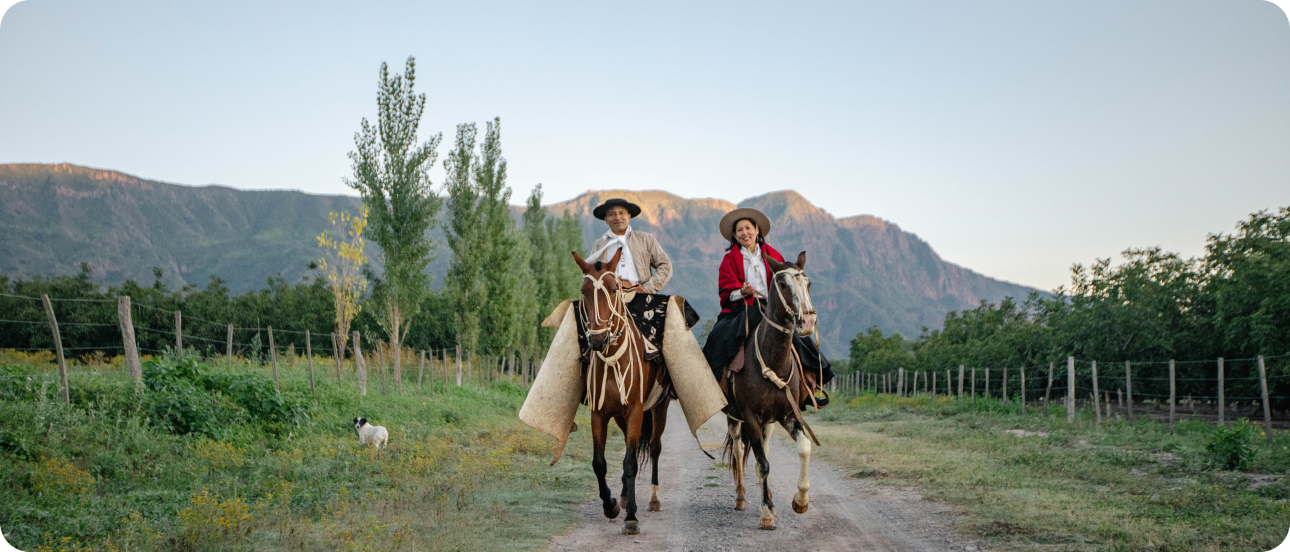 Two humans riding horses through the La Bodeguita Farm
