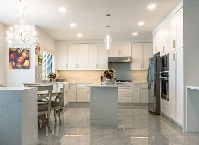 Bright white kitchen renovation with an island, tile floors, and a chandelier in Ottawa