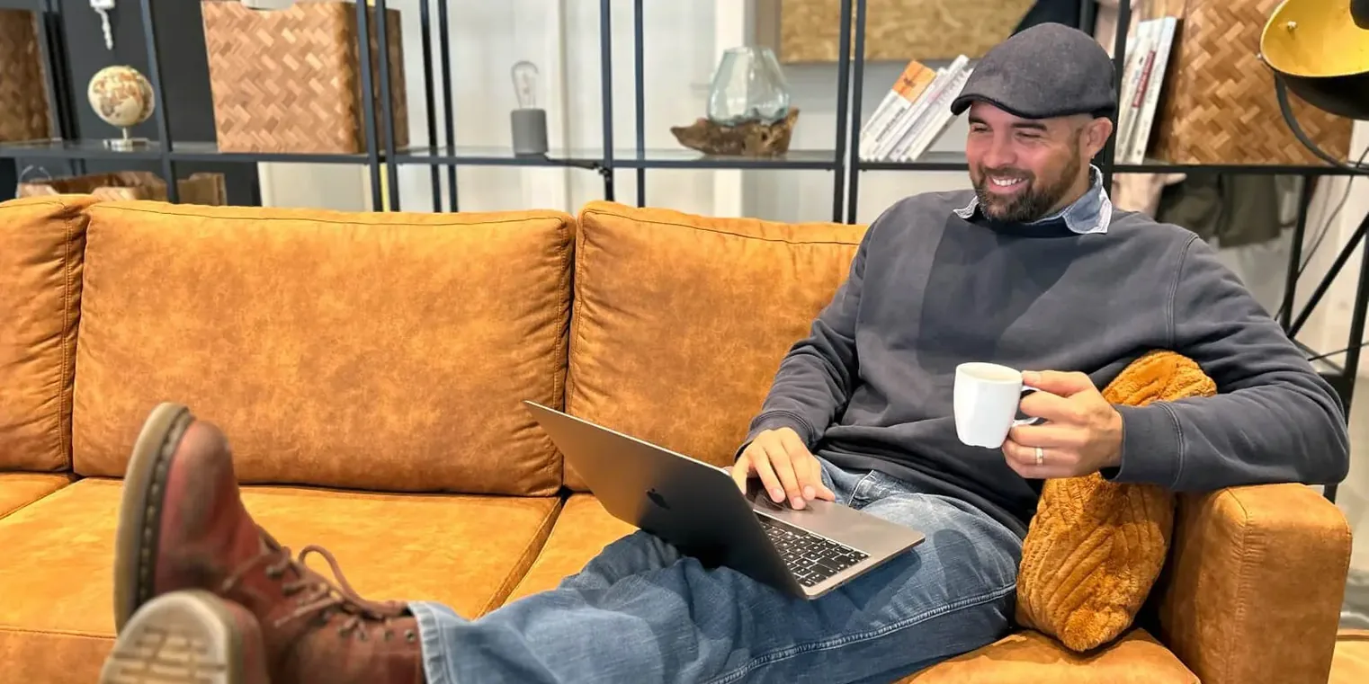 Een foto van Stephanus van Vuuren op de bank met zijn laptop en koffie