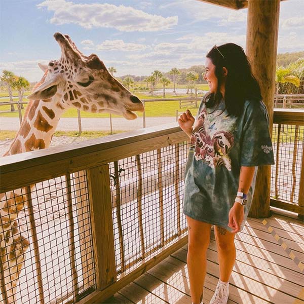Guest smiling at reticulated giraffe from the giraffe feeding platform at Wild Florida Adventure Park.