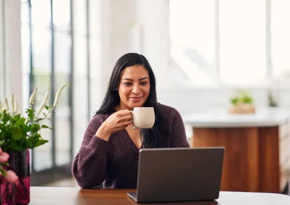 Woman looking at a laptop and drinking coffe