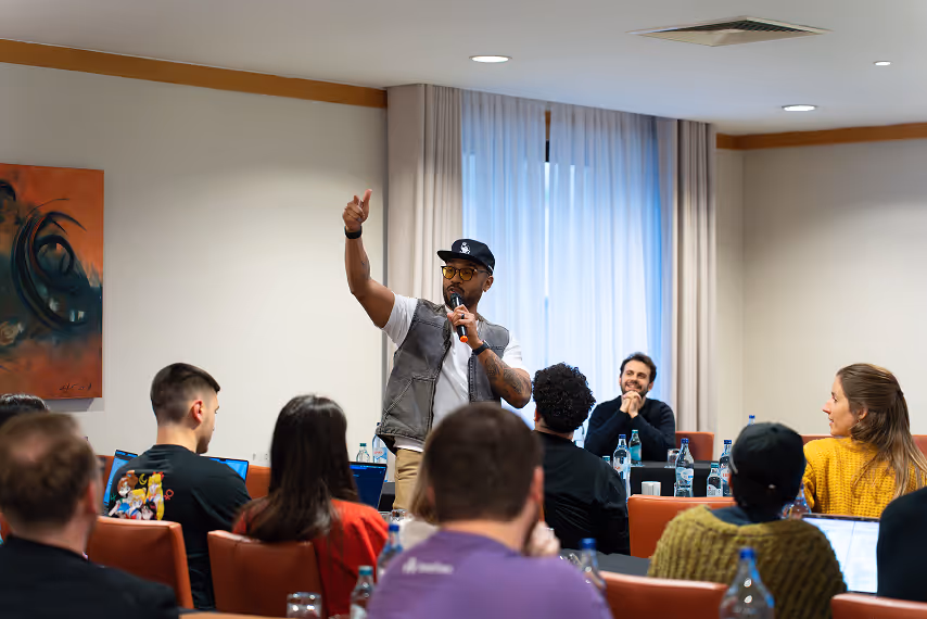 Speaker presenting with microphone to engaged Beefree team during an indoor workshop or team meeting session.