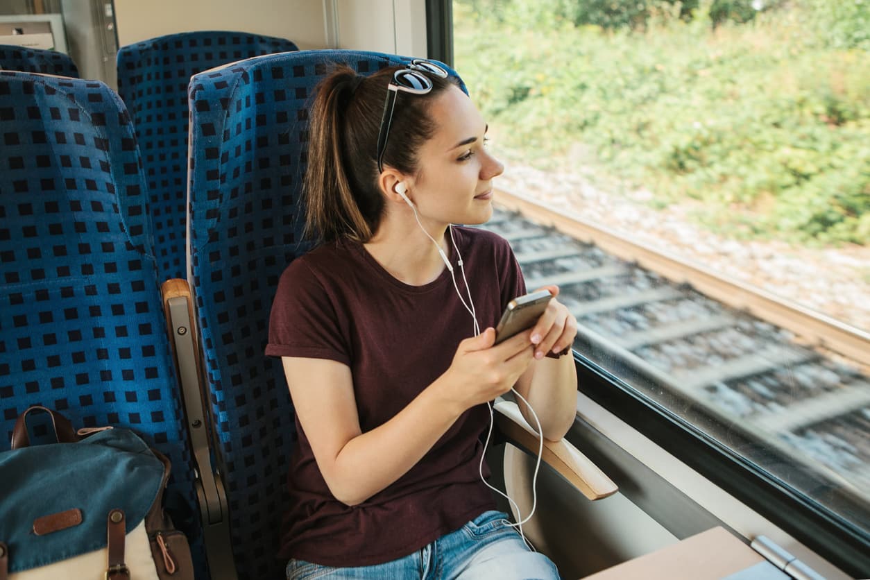 Ein junges Mädchen hört Musik oder Podcasts während der Reise in einem Zug