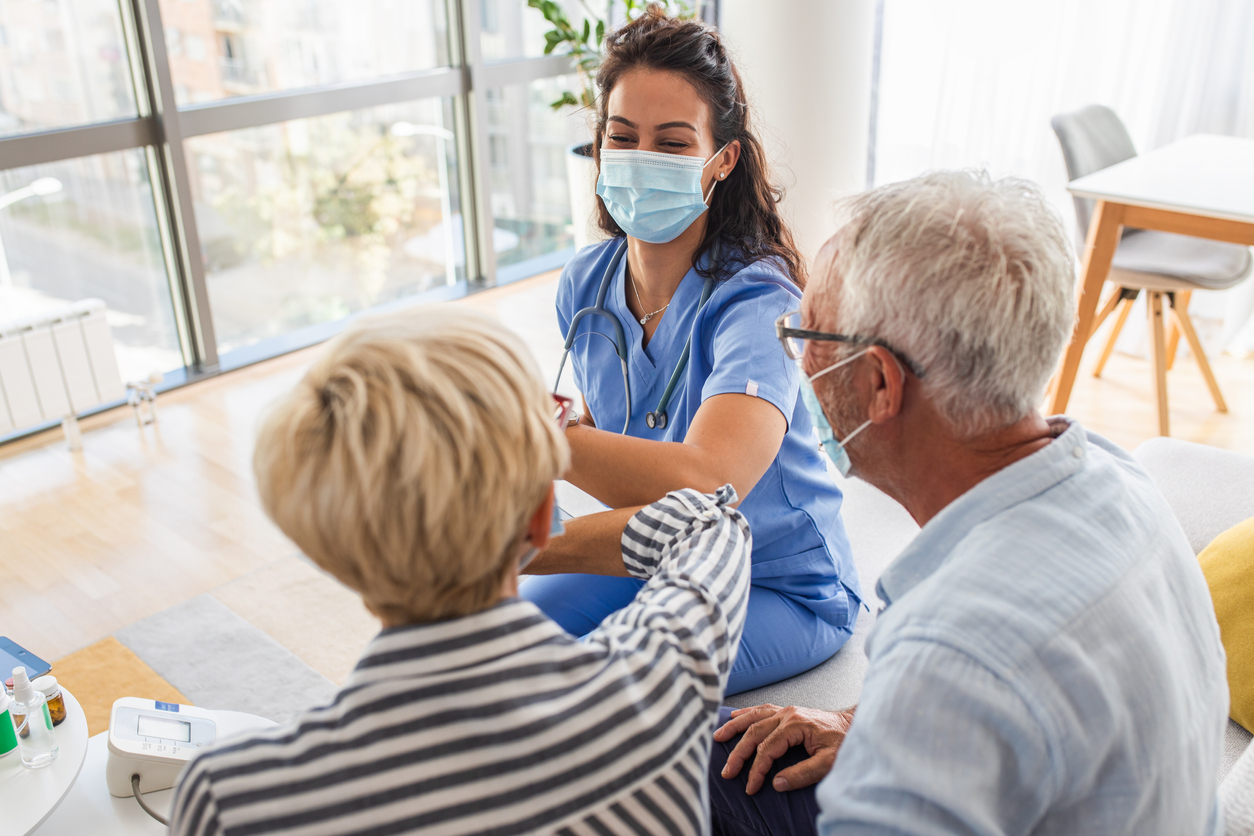 Weibliche Krankenschwester Gruß mit Senioren Patienten mit Maske.