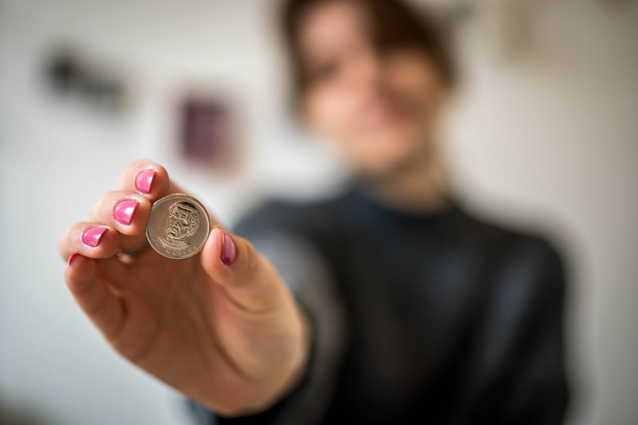 Frau hält Münze in die Kamera