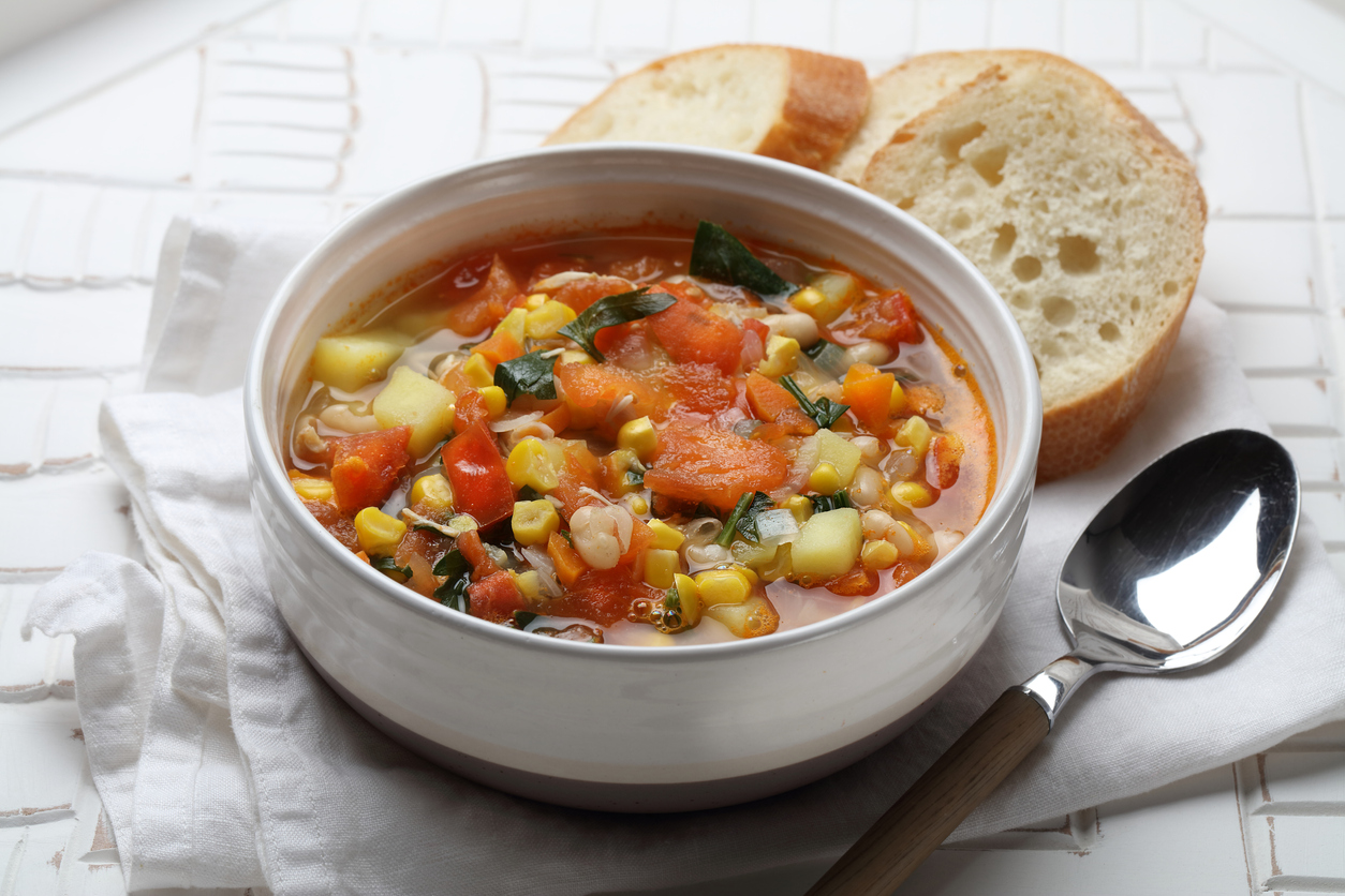 Saisonale Gemüsesuppe mit Kartoffeln, Karotten, Zwiebeln, Knoblauch, weißen Bohnen, Mais, Tomaten