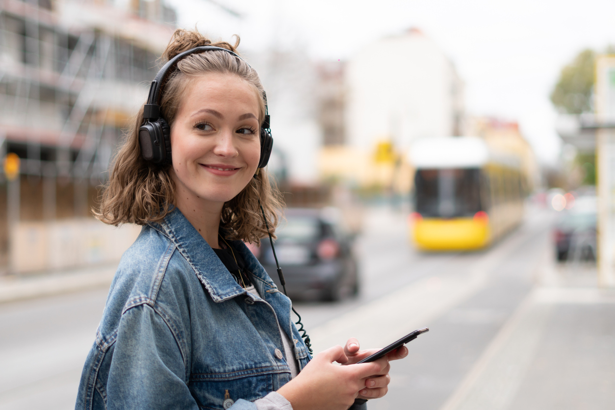 Frau mit Kopfhörern geht über eine Straße