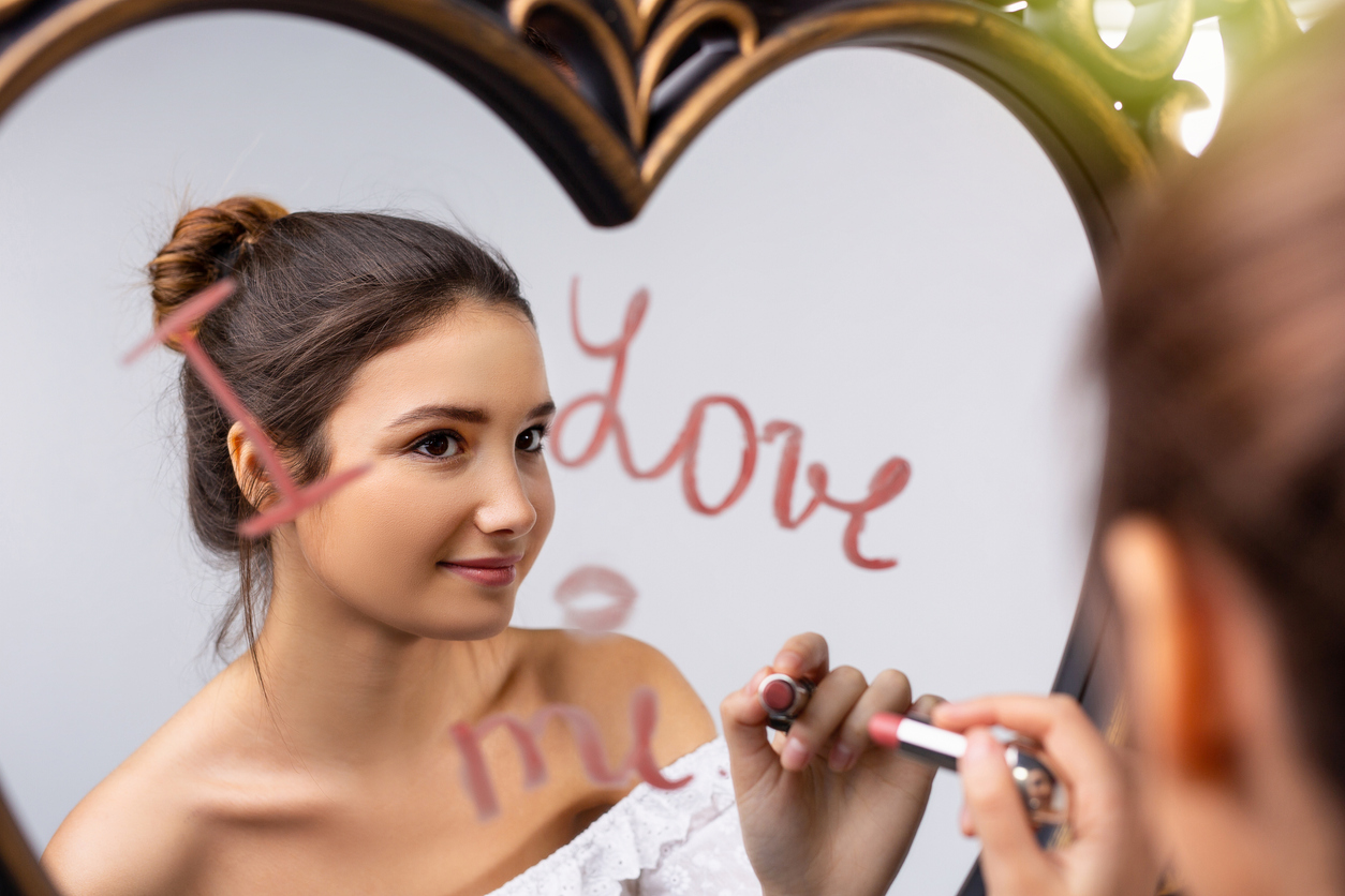 Frau schreibt „I love me” an Spiegel