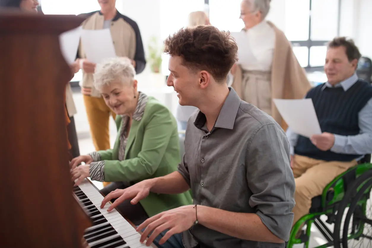 Seniorin mit jungem Lehrer, der in der Chorprobe Klavier spielt