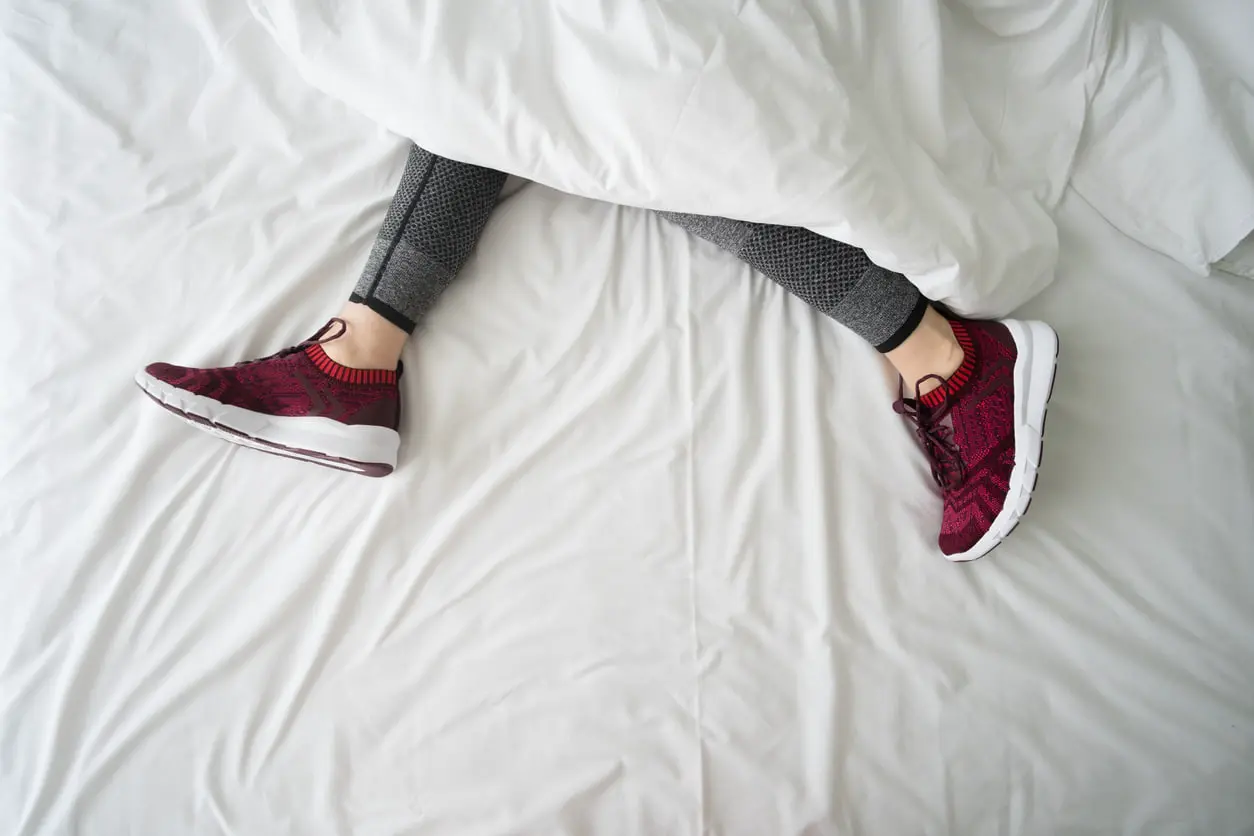 Frau trägt Turnschuhe im Bett