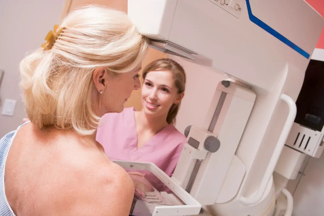 breast care nurse unterstützt patientin bei mammografie