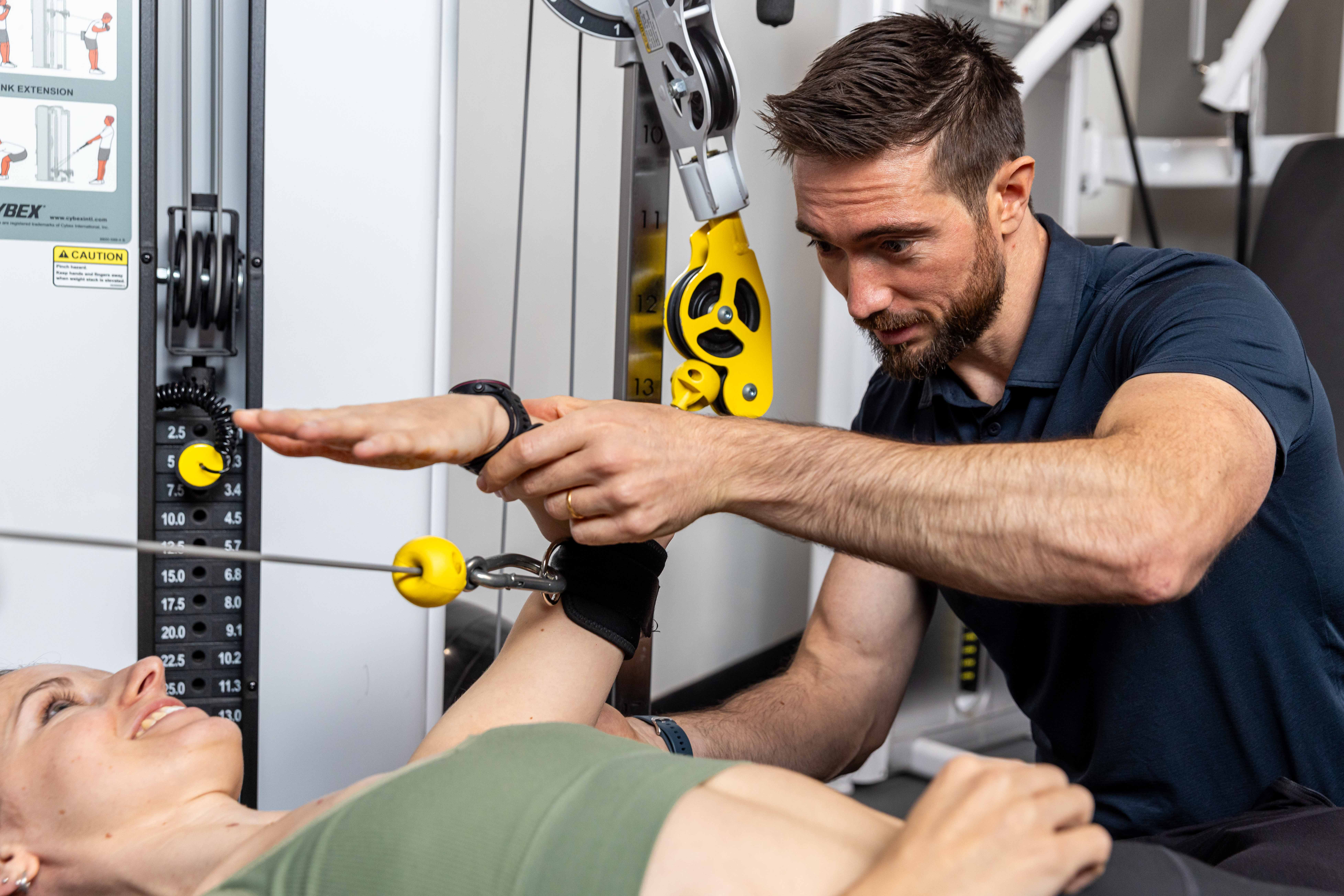 Strength House personal training session: trainer assisting client with shoulder exercise form in London studio