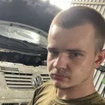 A man standing in front of a car under a hood.