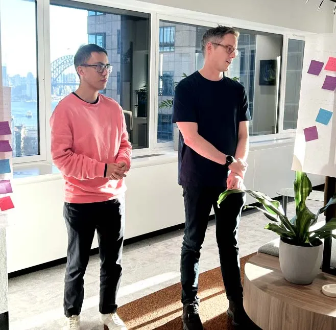 Two people working at their desks and laughing.