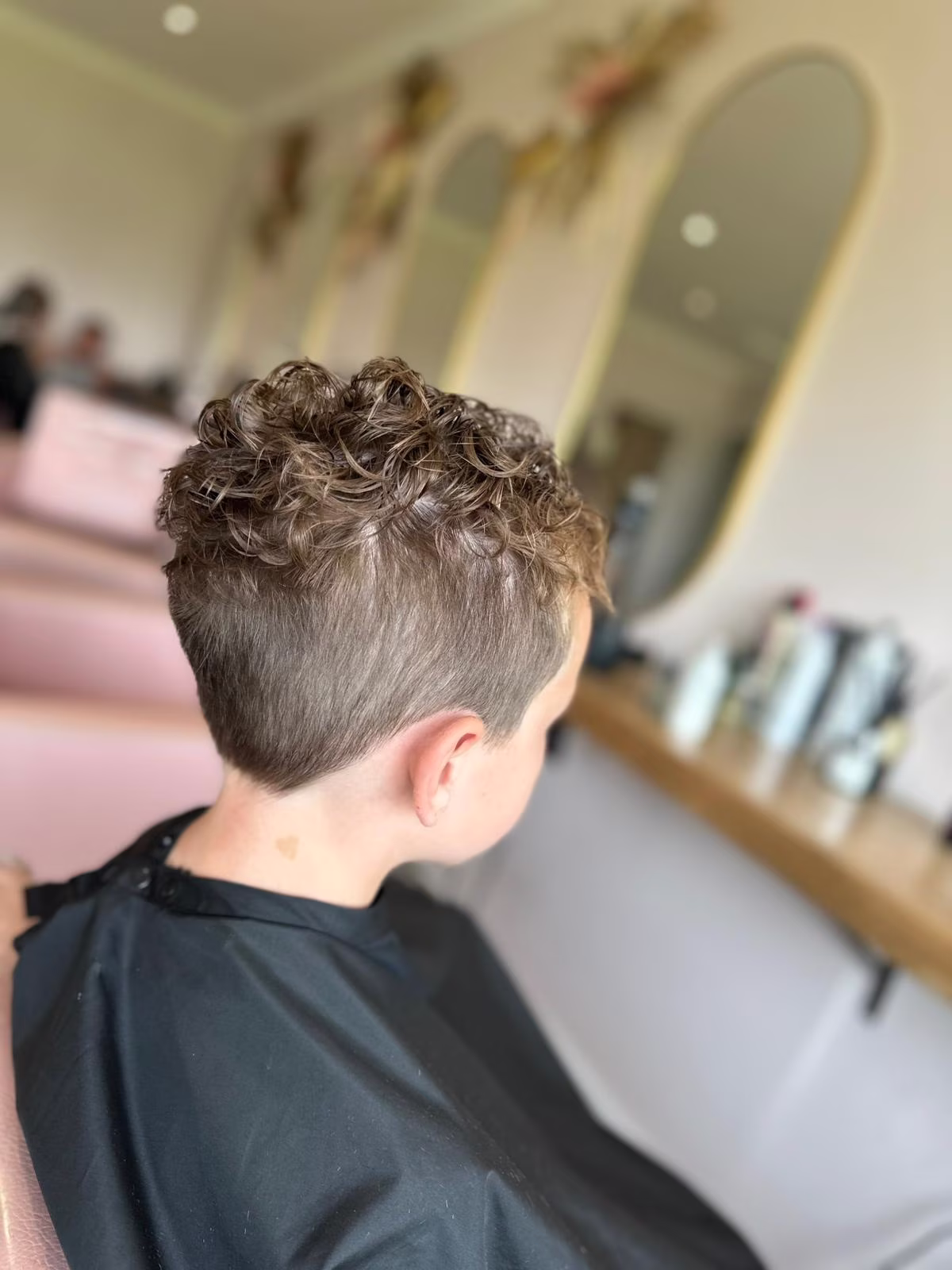 Boys hair cut shaved at the side, with curls on top