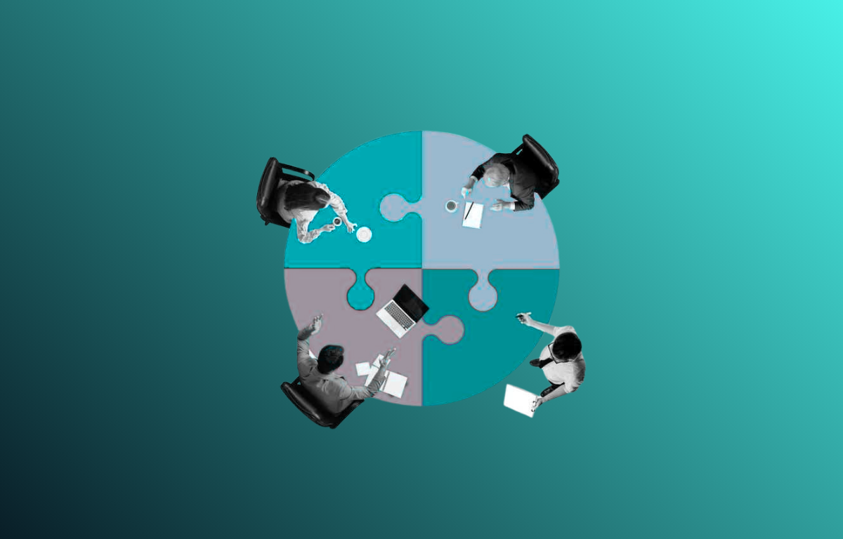 Four people at a round table with a puzzle-shaped surface, viewed from above
