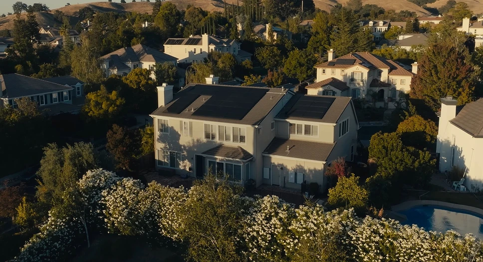 Aerial view of a suburban home with new Tesla solar panels on the roof