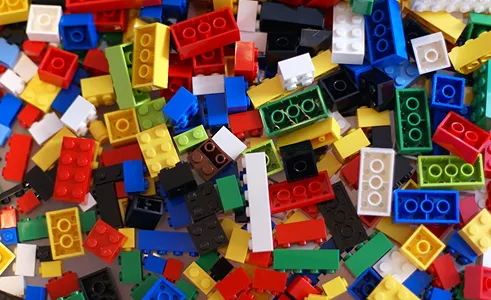 Pile of colorful interlocking plastic building blocks in various shapes and sizes.