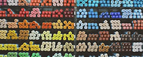 Rows of multicolored pastel chalk sticks organized by color gradient on a black surface.