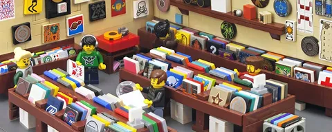 Lego minifigures browsing and working inside a colorful Lego bookstore with books and posters.