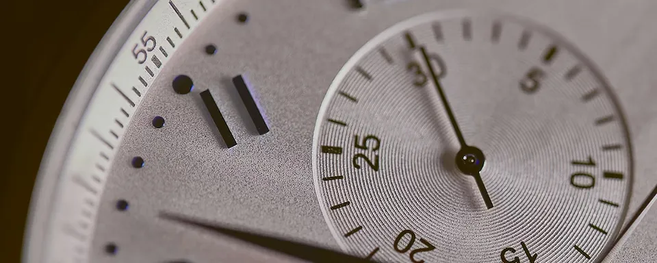 Close-up of a silver watch dial showing hour, minute, and second markers with a smaller sub-dial.