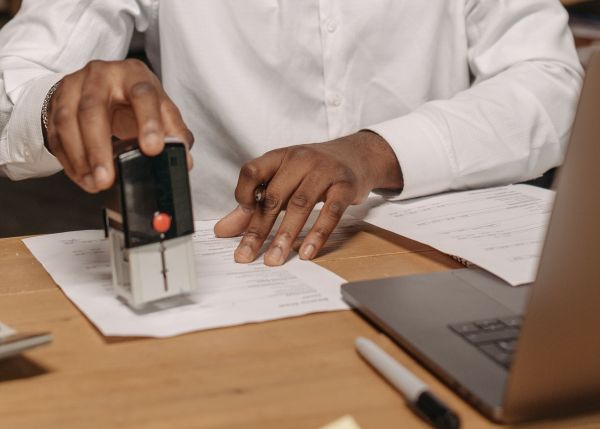Man in a white dress shirt stamping paperwork.