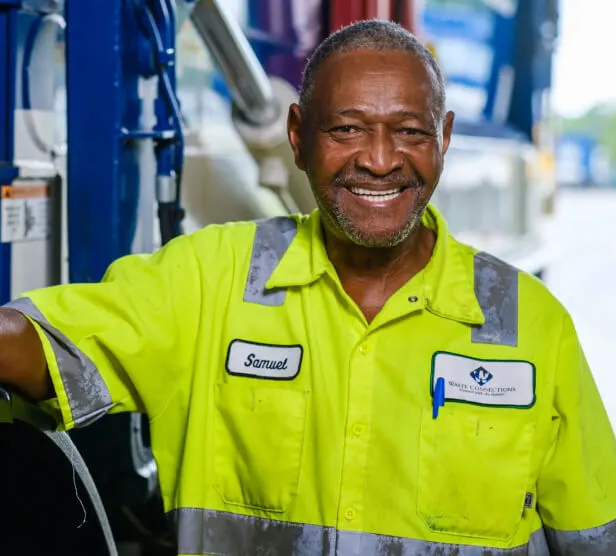 Waste service representative with tablet standing by a commercial trash dumpster.