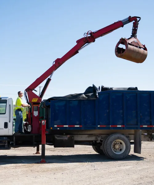 Waste service representative with tablet standing by a commercial trash dumpster.