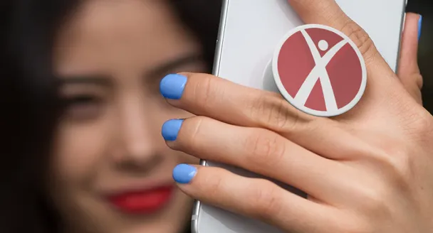 Women holding up her phone with a Fitness Connection pop socket displayed between her fingers