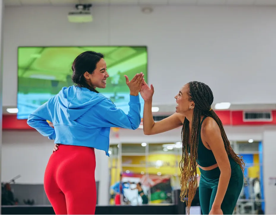 two women high-fiving celebrating their achievements in fitness