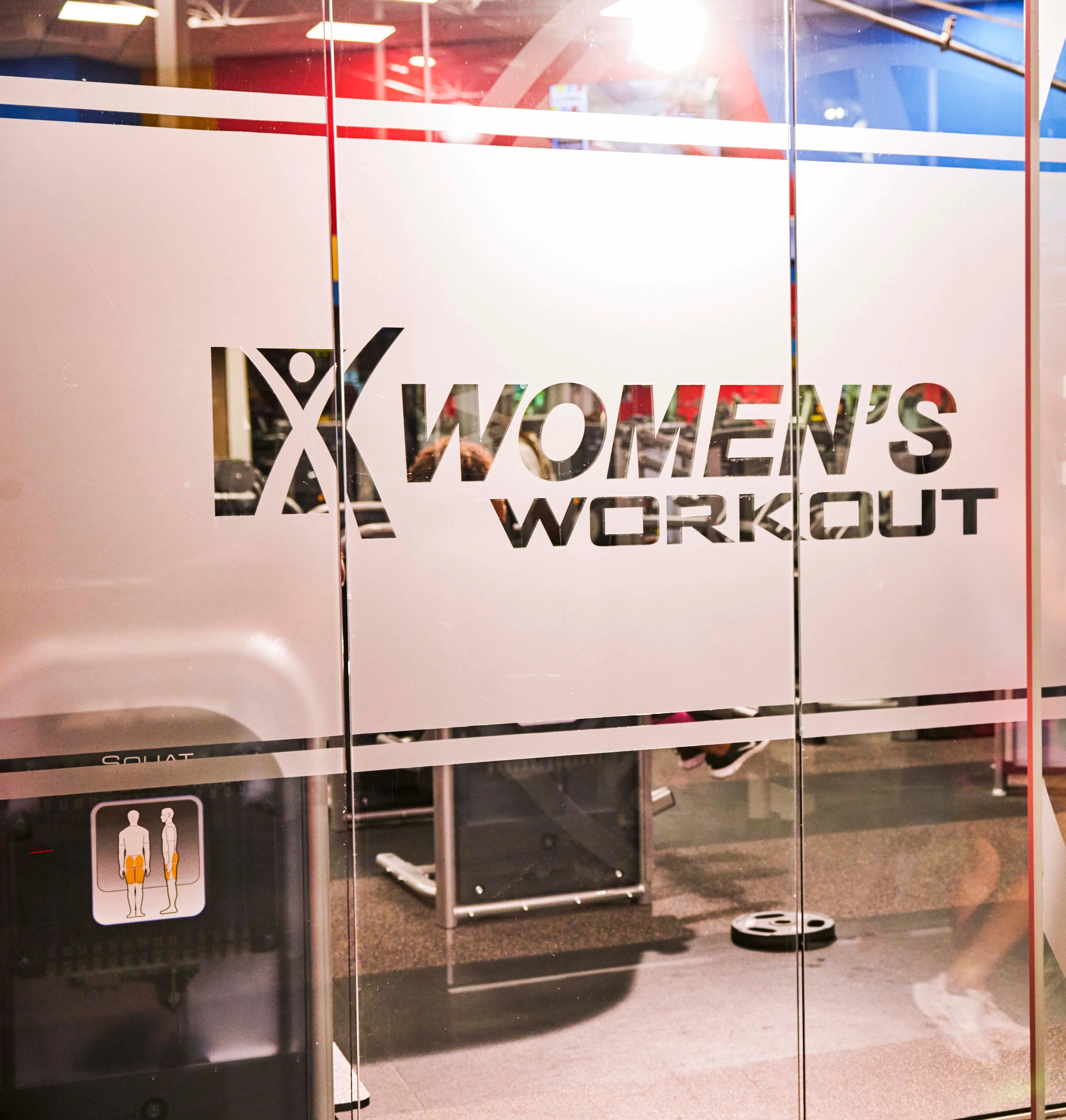 A glass window with Women's Workout etched on a frosted border.