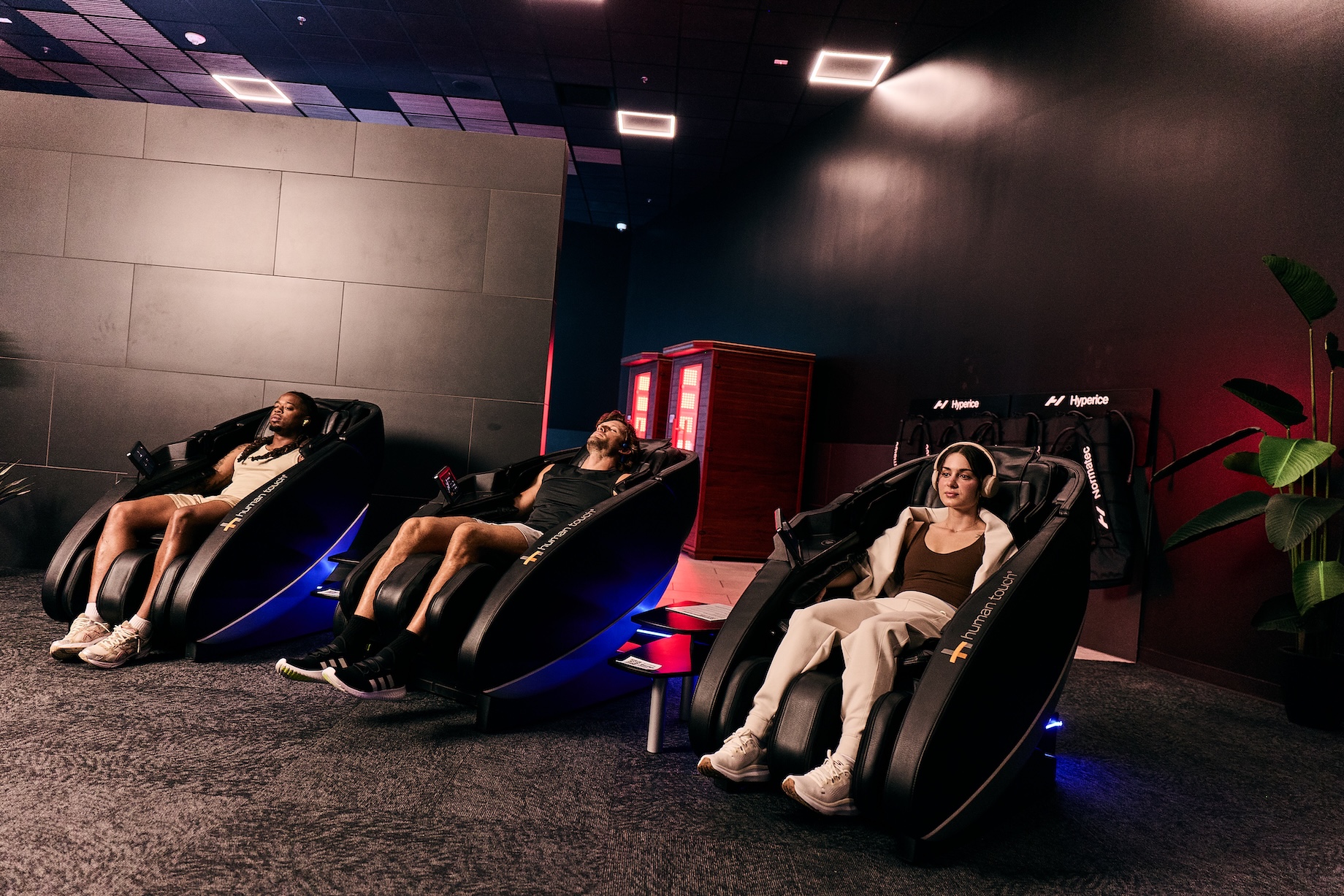 two men and a woman relaxing in massage chairs