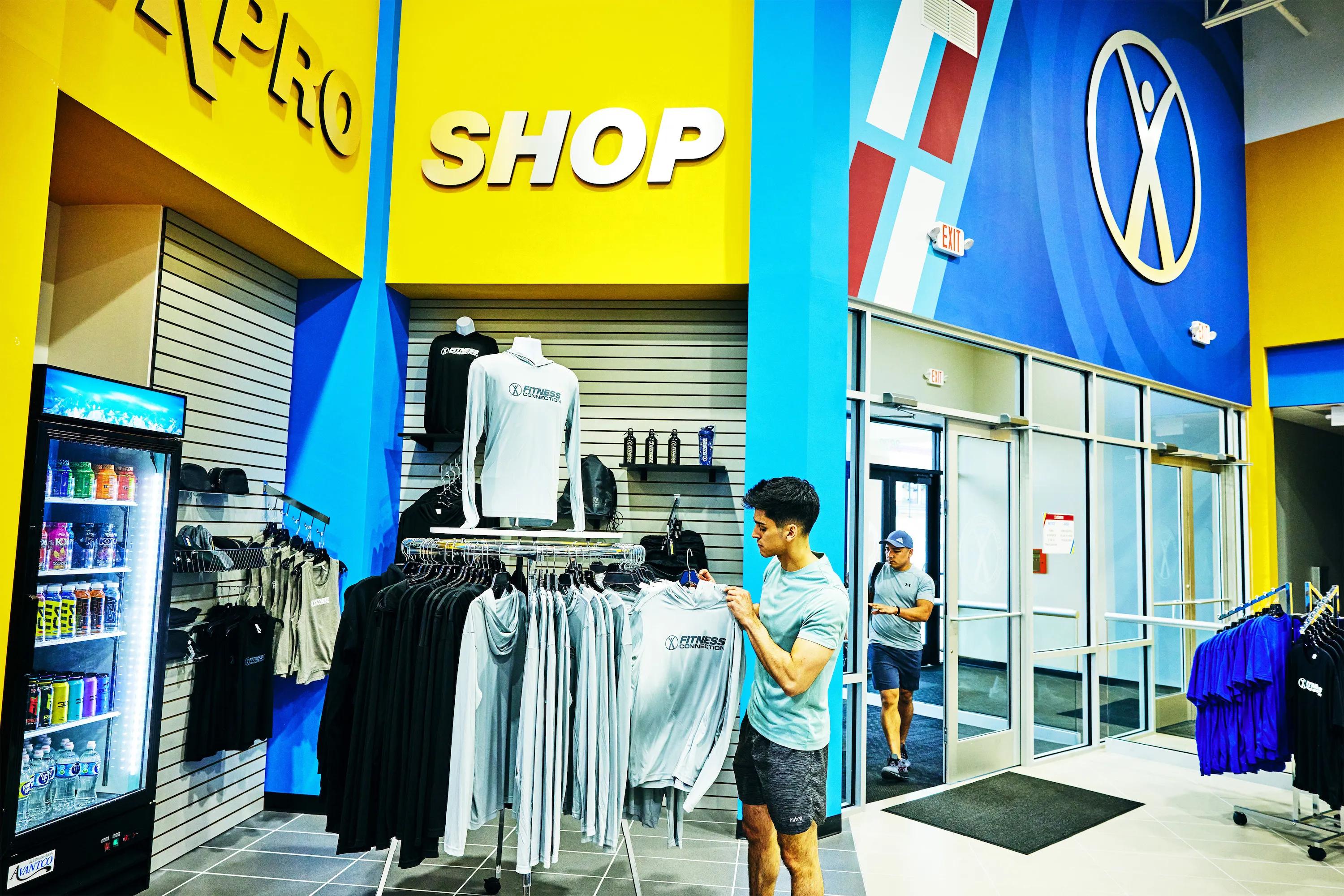 A young man holding a Fitness Connection shirt, shopping