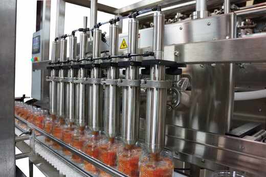 Multi-head piston food dispenser filling jars on a production line