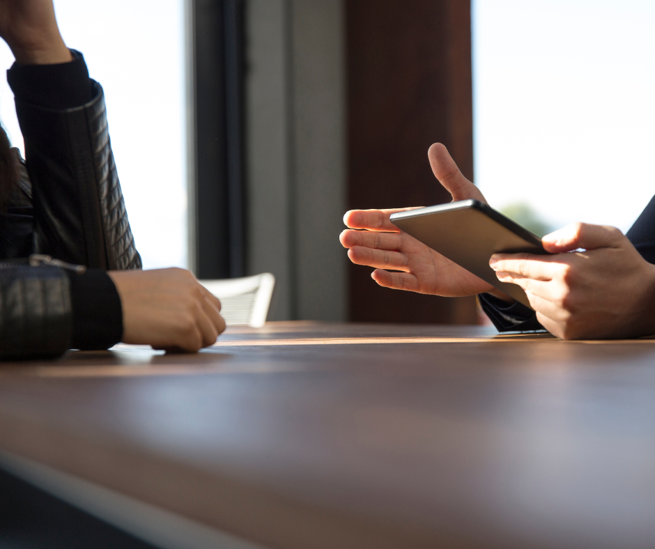 This images shows the hands of two people in discussion over a board room table.
