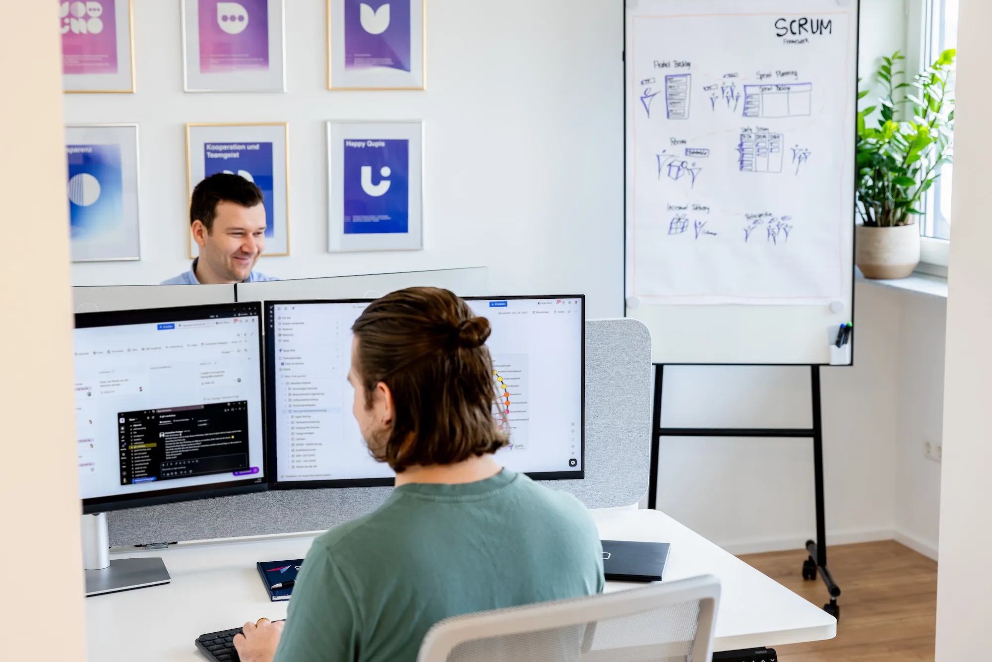 Eine Person präsentiert oder erklärt Inhalte auf einem großen Bildschirm in einem gut beleuchteten Büro