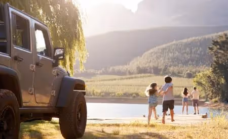 Jeep parked by a lake while a family heads to the water