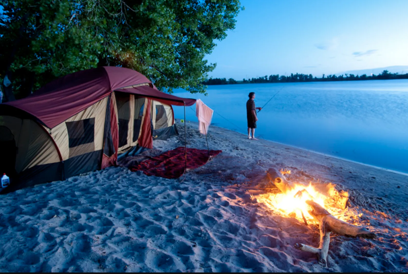 Campfire and tent on a sandy beach at Lake McConaughy