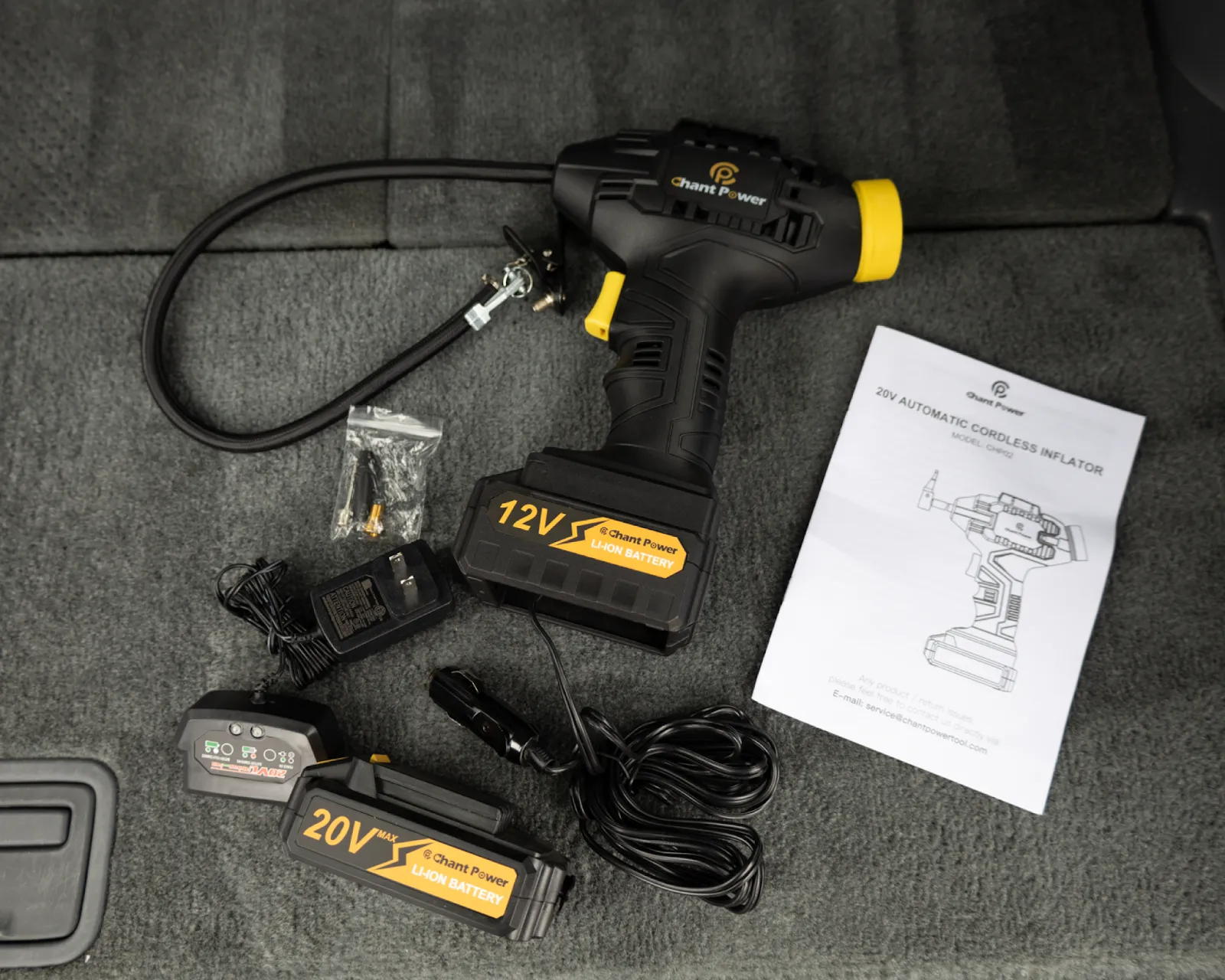 Cordless tire inflator with batteries and charger on a car floor