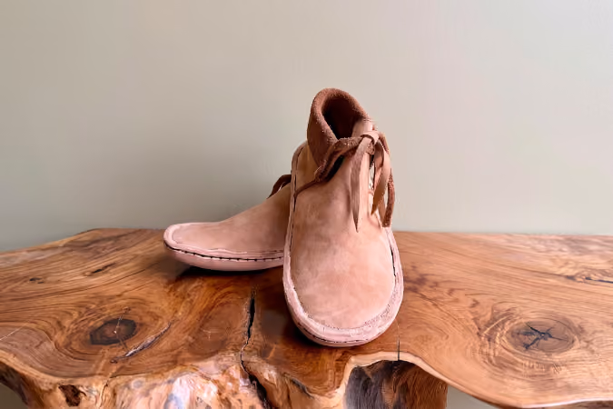Pale pink leather moccasins on a wood table