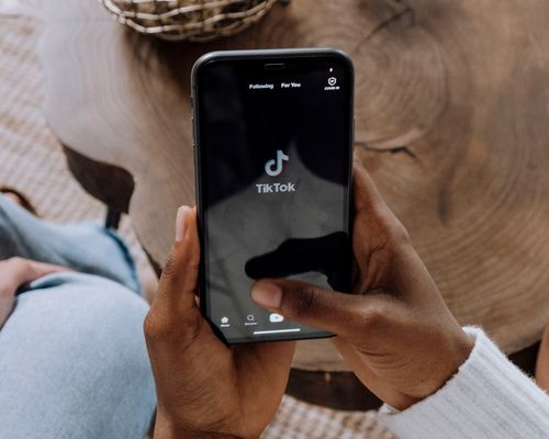 a person holding up their phone with the TikTok logo on the screen
