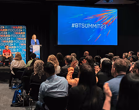 Lady speaking to a crowd in a room at a Barfoot & Thompson Training session
