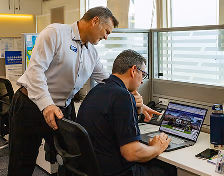 Picture of Manager giving advice to his salesperson who is sitting at this laptop