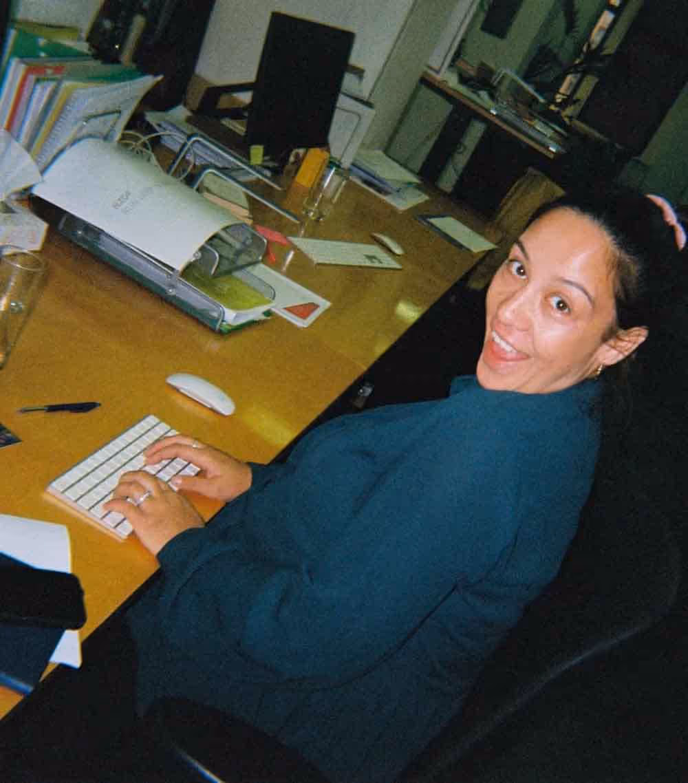 A woman smiling at her desk while typing on a keyboard, offering a glimpse into daily life in a creative advertising role.
