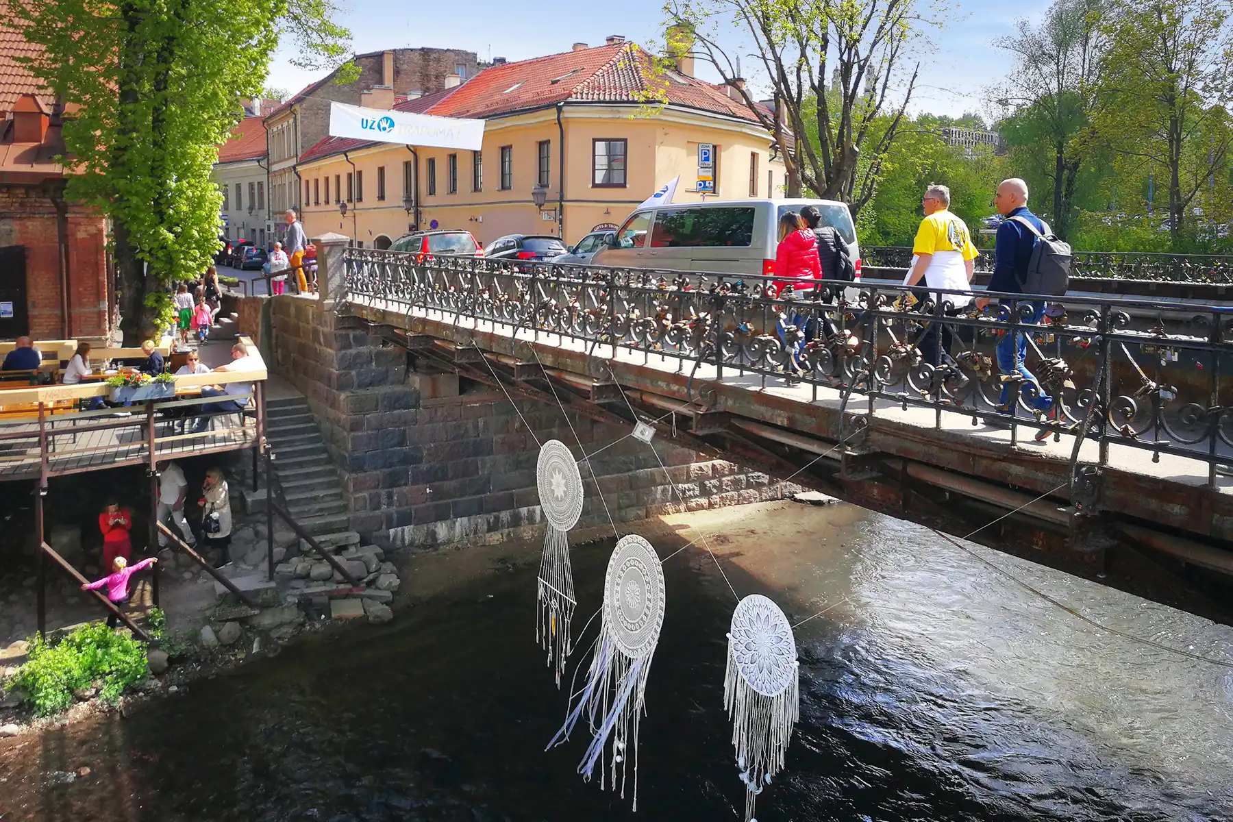 Мост над река във Вилнюс с тераси, зеленина и арт инсталации по бреговете