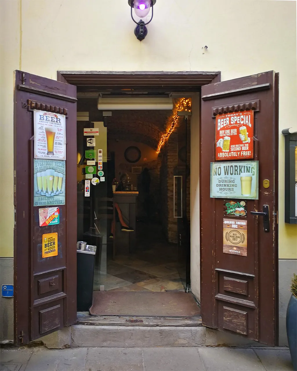 Гостоприемно разтворени дървени порти на бар със забавни табели във възхвала на бирата